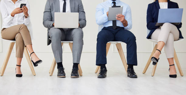 istock Unknown group of diverse businesspeople waiting for interview and using technology. Team of applicants sitting together. Professional candidates in line for job opening, vacancy and office opportunity 1403403905
