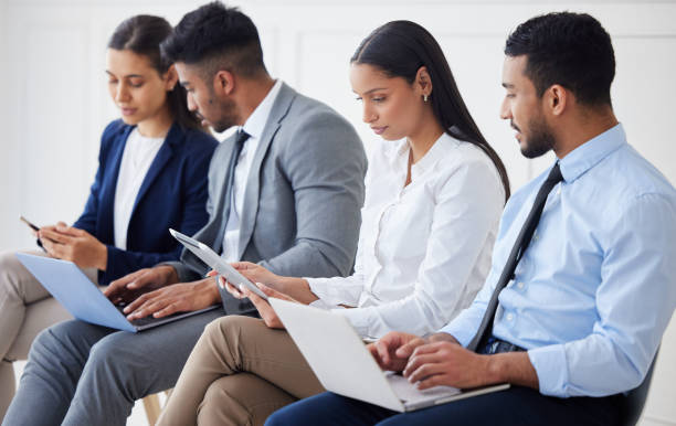istock Group of diverse businesspeople waiting for interview and using technology. Team of young applicants sitting together. Professional candidates in line for job opening, vacancy and office opportunity 1403408602