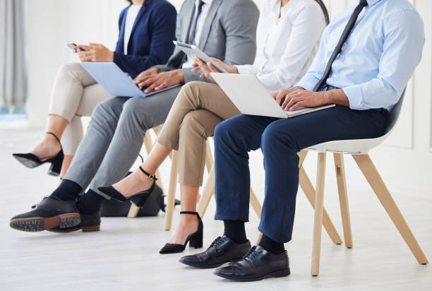 istock Unknown group of diverse businesspeople waiting for interview and using technology. Team of applicants sitting together. Professional candidates in line for job opening, vacancy and office opportunity 1403408768