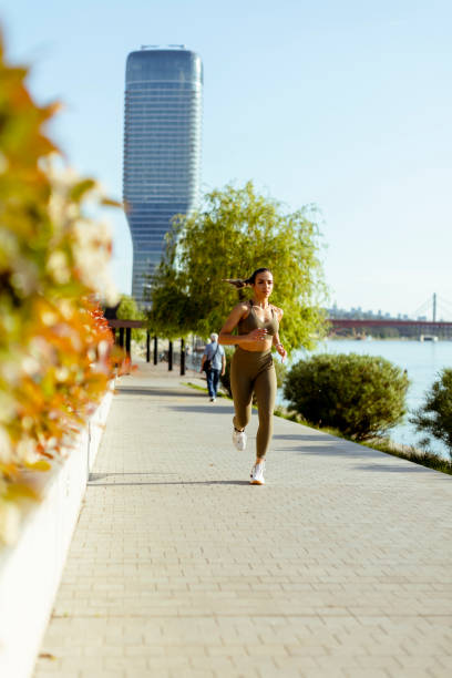 istock Young woman taking running exercise by the river promenade 1403409501