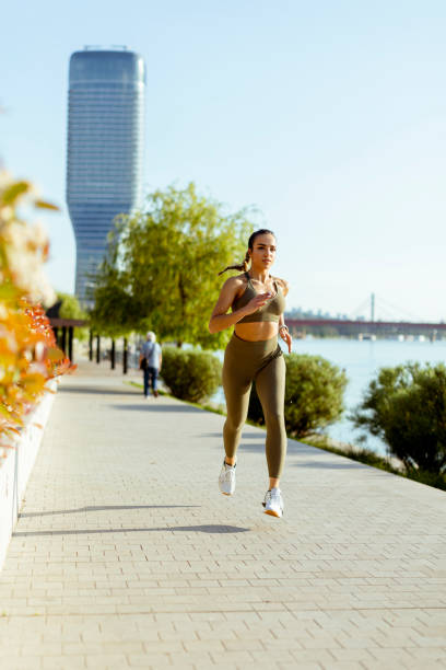 istock Young woman taking running exercise by the river promenade 1403409512
