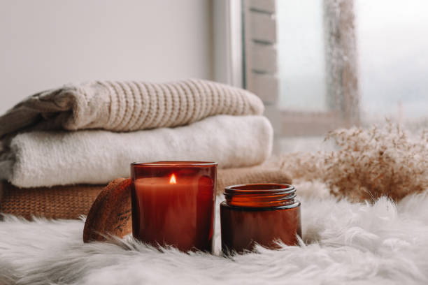 istock Two candles on the windowsill with sweaters. Autumn mood. 1403411218