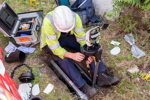 16th June 2022: A BT Openreach engineer, sitting on the ground connecting superfast fibre broadband which is being installed in a rural location in Scotland. This will enhance the lives of residents who have been held back from working effectively from home and being able to use online services, having not had the same internet capacity as those living in cities and towns.
