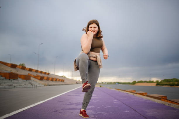 european teenage girl overweight on jog on treadmill along embankment of city, overweight and active lifestyle of teenager - teen obesity imagens e fotografias de stock