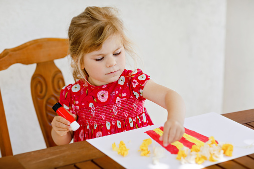 Pequeña niña creativa pintando con la caja de palomitas de maíz de colores de los dedos y haciendo callos de papel con pegamento. Niño activo divirtiéndose dibujando haciendo manualidades. Educación para niños. Actividad creativa. photo