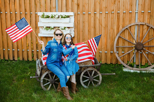 Mom and daughter have fun and celebrate on the background of the American flag. Independence Day