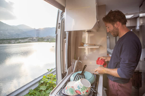man doing the dishes in her van - plate changing imagens e fotografias de stock