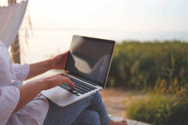Pretty young woman surfing internet on laptop outdoors stock photo