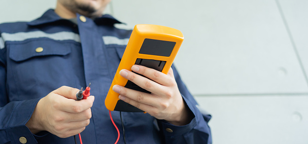 close up electrician engineer hand hold multimeter to use about measure voltage or ampere current in industry factory for system control and technical maintenance concept