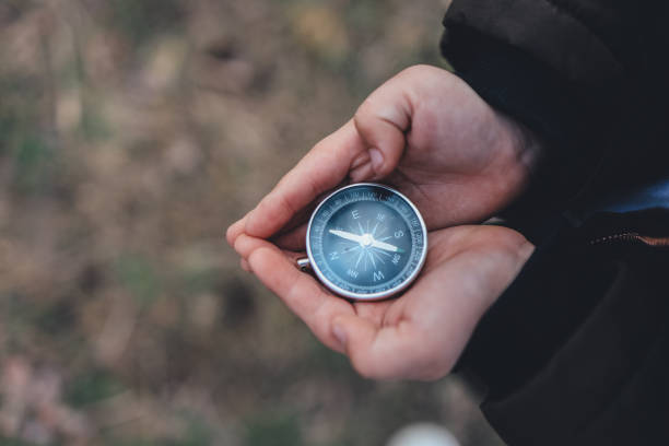 istock Navigation compass in hand. Travel and camping in forest. Finding path and direction 1403419134