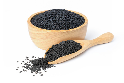 Black sesame seeds in wooden bowl and scoop isolated on white background.