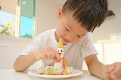 子供のための簡単で楽しいマシュマロ雪だるまの食用工芸品を作る台所に座ってかわいい男の子の子供