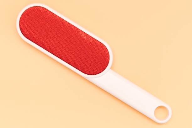 la vue de dessus d’une brosse à vêtements électrostatique rouge pour enlever la fourrure de chat se trouve sur un fond jaune. manche. charpie. pelucheux. pile. confusion. litière. méchant. tas. blanc. textile. duvet. ordonné. ordures - lint remover photos et images de collection