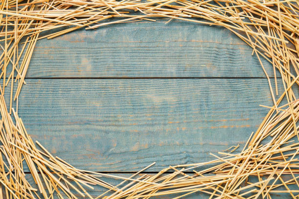 istock Frame of dried hay on light blue wooden background, flat lay. Space for text 1403424926