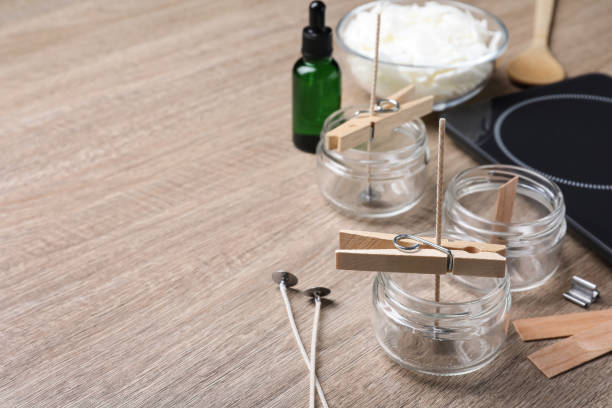 istock Glass jars with wicks and clothespins as stabilizers on wooden table, space for text. Making homemade candles 1403424984