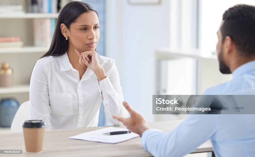Mixed race hiring manger in interview with businessman. CEO with resume and cv of candidate looking for job opening, vacancy, office opportunity. Applicant sitting and explaining experience to hr boss Discussion Stock Photo