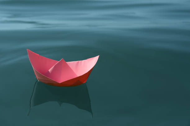 istock Pink paper boat floating on water surface, space for text 1403425316