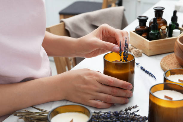 frau, die hausgemachte kerze mit lavendelblumen am tisch drinnen dekoriert, nahaufnahme - homemade stock-fotos und bilder