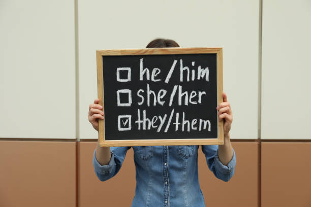 kobieta trzymająca tablicę z listą zaimków płciowych w pobliżu kolorowej ściany - gender symbol zdjęcia i obrazy z banku zdjęć