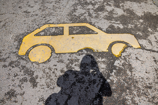 Yellow marking of a car on a asphalt road and the photographers shadow