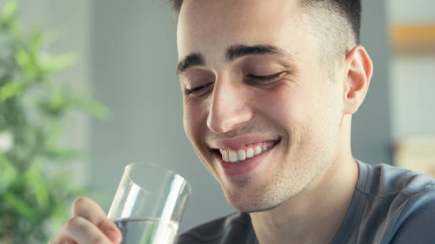 istock Young man drinks a glass of water 1403426818