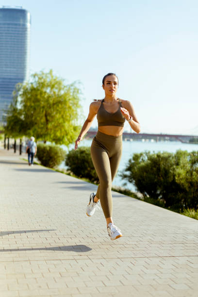 istock Young woman taking running exercise by the river promenade 1403429654