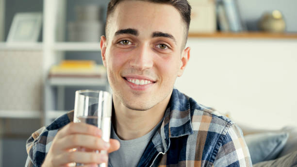 istock Young man drinks a glass of water 1403431250