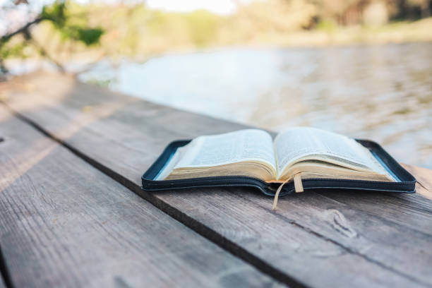 istock Open Bible on a wooden board near the river 1403432397
