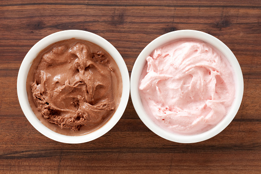 Top view of two bowls side by side with chocolate and strawberry ice cream