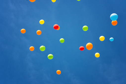 Holiday attributes: A large bunch of multi-colored inflated balloons with ribbons, isolated on a white background