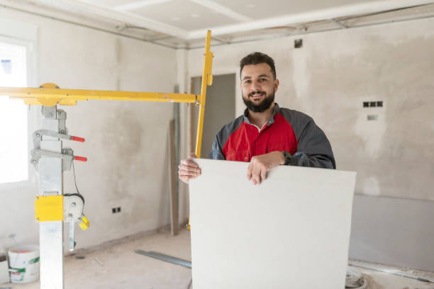 Construction worker installs plasterboard ceilings and insulation. drywall ceiling stock photo