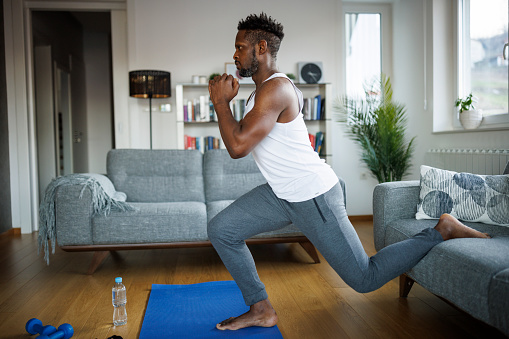 Strong athletic fit man exercising at his home