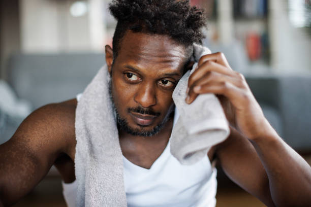 istock Portrait of athletic man wiping sweat from forehead after exercise at home 1403436708