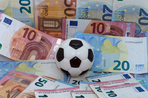 Symbol image: sport and money, football against a background of banknotes