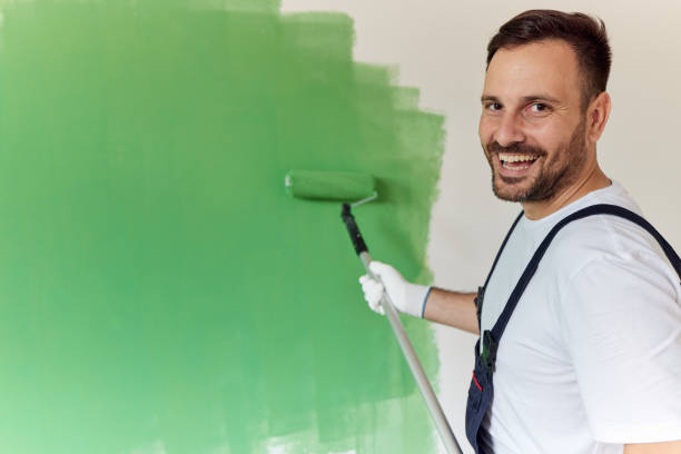 istock Happy house painter painting the wall in green. 1403437336