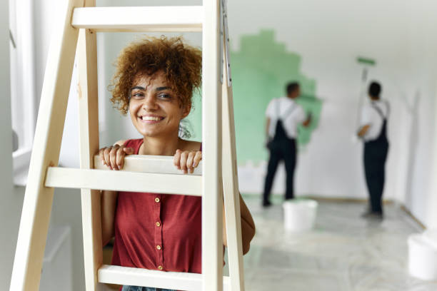 istock Young happy woman looking through ladder during home renovation process. 1403439338