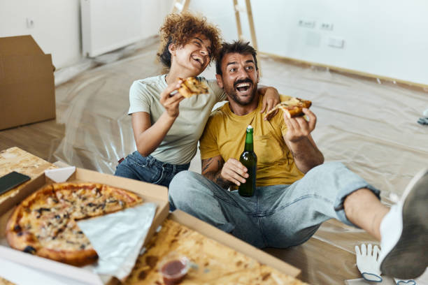 istock Cheerful couple having fun while eating pizza at their renovating apartment. 1403439364