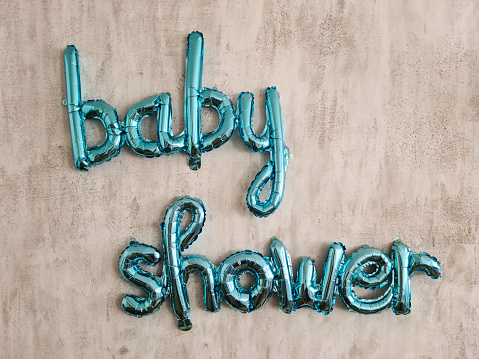 Blue baby shower balloon sign on the wall indoors.