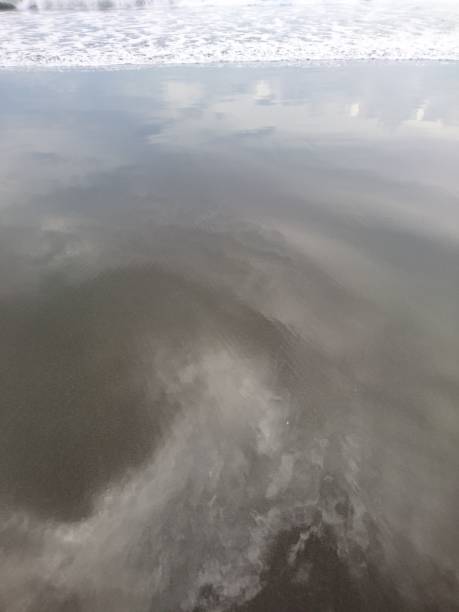 istock Reflection of clouds on the beach sand 1403441231