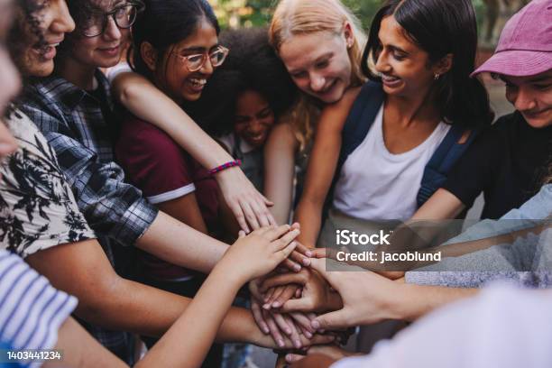 Cheerful Teenagers Putting Their Hands Together In Unity Stock Photo - Download Image Now