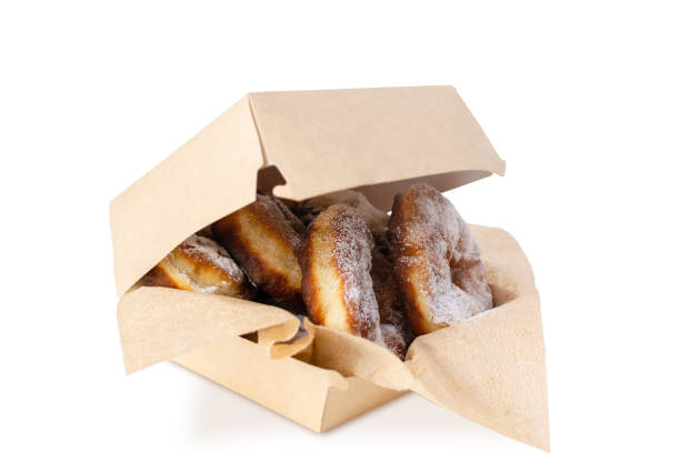 istock Homemade doughnuts sprinkled with powdered sugar on kraft napkins in a slightly open box. Baked donuts. Delivery service and sale in a sweet pastry shop, confectionery. 1403444897