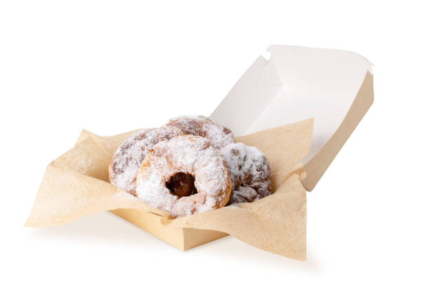istock Doughnuts sprinkled with powdered sugar on kraft napkins in an open cardbox. Donuts. Delivery service and sale in a sweet pastry shop, confectionery. 1403444934