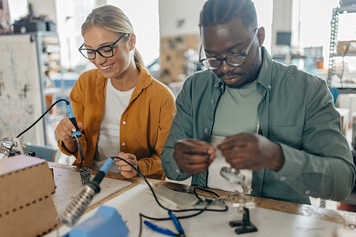 Ona male african American and one Caucasian female student soldering electrical components