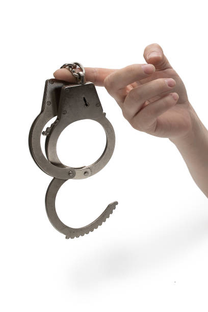 istock Metal handcuffs with a chain on a light background in a female hand 1403448523