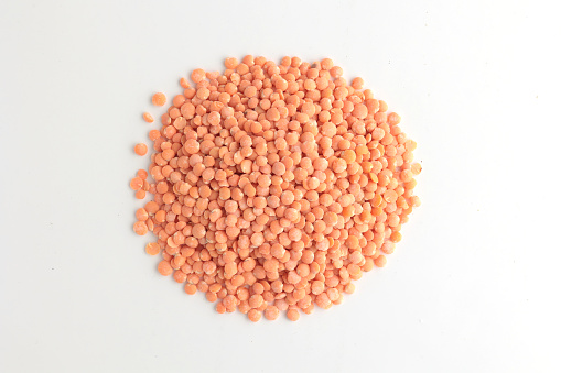 Red lentils on a wooden spoon - isolated oon white