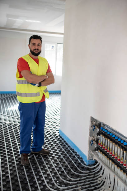 istock Man installs and checks underfloor heating, smiling at camera 1403448943