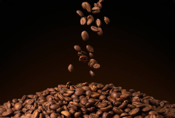 летит вниз падения коричневые кофейные зерна на черном фоне - caffeine full frame studio shot horizontal стоковые фото и изображения