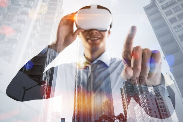 istock Attractive happy young man with vr glasses standing and pointing finger on abstract double exposure city background. Virtual reality and metaverse concept. 1403451035
