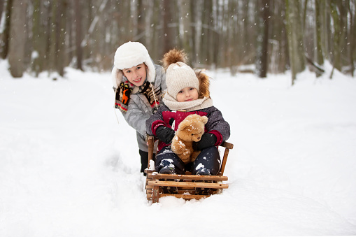 Children on a wooden sled on a winter day. Active winter kids outdoors games
