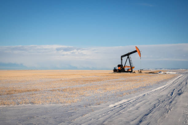 Oil Pump in Winter Small oil pump in field covered in snow with copy space. oil pump oil industry alberta equipment stock pictures, royalty-free photos & images